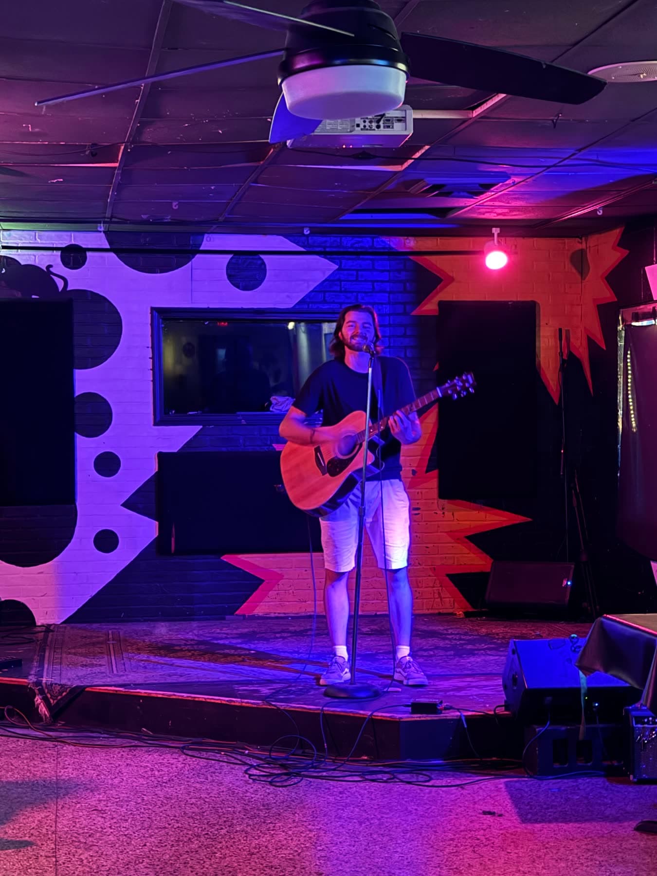 Solo acoustic set against the painted stage wall